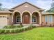 Inviting home exterior with arched entryway, complemented by lush landscaping and green lawn at 2409 Heather Manor Ln, Lutz, FL 33549
