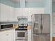 A modern kitchen features stainless steel appliances, granite countertops, and white cabinetry at 2409 Heather Manor Ln, Lutz, FL 33549