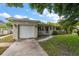 Charming home featuring a well-manicured lawn, a driveway, an attached garage, and lovely landscaping at 4321 S Thatcher Ave, Tampa, FL 33611
