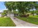Charming home featuring a well-manicured lawn, a driveway, an attached garage, and lovely landscaping at 4321 S Thatcher Ave, Tampa, FL 33611