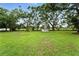 Expansive backyard featuring lush green grass, mature trees, and a storage shed at 4708 Bugg Rd, Plant City, FL 33567
