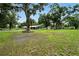 Spacious backyard with mature trees and a view of the house with covered parking at 4708 Bugg Rd, Plant City, FL 33567