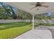 Backyard with lush green lawn, trees, and a white fence, viewed from a covered patio with ceiling fan at 4717 W Anita Blvd, Tampa, FL 33611