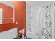 Bathroom with orange wall and tub/shower combo with white tile and damaged wall at 4717 W Anita Blvd, Tampa, FL 33611