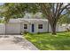 Charming single-story home featuring a well-manicured lawn and a blue front door under the shade of a mature tree at 4717 W Anita Blvd, Tampa, FL 33611