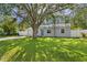 Charming single-story home featuring a well-manicured lawn and a blue front door under the shade of a mature tree at 4717 W Anita Blvd, Tampa, FL 33611