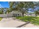 Charming single-story home featuring a well-manicured lawn and a blue front door under the shade of a mature tree at 4717 W Anita Blvd, Tampa, FL 33611