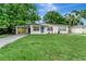 Charming single-story home with a carport, a blue door, manicured landscaping, and lush green lawn at 517 Fairhope Dr, Apollo Beach, FL 33572