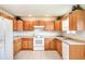 Traditional eat-in kitchen with tile floors, natural wood cabinets, and white appliances at 7841 Royal Stewart Dr, New Port Richey, FL 34653