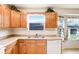 Eat-in kitchen with natural wood cabinets, stainless steel sink, and dishwasher under window at 7841 Royal Stewart Dr, New Port Richey, FL 34653