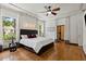 Bright bedroom featuring hardwood floors, a ceiling fan, and large windows allowing natural light to flood the room at 8600 Shenandoah Run, Wesley Chapel, FL 33544
