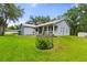 View of the house with a metal roof, manicured lawn, and tasteful landscaping at 8600 Shenandoah Run, Wesley Chapel, FL 33544