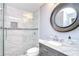 Stylish bathroom with a glass-enclosed shower and a marble countertop vanity with round mirror at 9481 Highland Oak Dr # 1506, Tampa, FL 33647