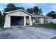 Beige home with attached garage, mature landscaping, and concrete driveway with tropical palms and blue sky at 10102 Missy Ct, Tampa, FL 33615