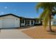 Inviting single-story home with palm tree, neutral exterior, attached garage and gravel yard at 10914 Oakdale Ave, Port Richey, FL 34668
