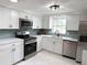 Modern kitchen featuring white cabinets, stainless steel appliances, granite countertops, and tiled backsplash at 10914 Oakdale Ave, Port Richey, FL 34668