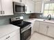 Modern kitchen featuring stainless steel appliances, white cabinetry, gray backsplash, and quartz countertops at 10914 Oakdale Ave, Port Richey, FL 34668