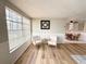 Bright living room featuring wood floors, large window, two chairs, and an open view to the dining area at 10914 Oakdale Ave, Port Richey, FL 34668