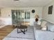 Cozy living room with sleek hardwood flooring, light gray walls, and view of the enclosed porch at 10914 Oakdale Ave, Port Richey, FL 34668