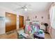 Bright bedroom features twin bed, ceiling fan, and neutral tile flooring at 11422 Brown Bear Ln, Port Richey, FL 34668