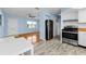 Open-concept kitchen with stainless steel appliances and modern flooring; dining area and living room visible at 12400 Park Blvd # 311, Seminole, FL 33772