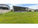 Grassy backyard area featuring an enclosed lanai, a white picket fence and nearby homes at 13334 Palmera Vista Dr, Riverview, FL 33579