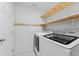 Functional laundry room with modern washer and dryer, plus wooden shelves for storage at 13334 Palmera Vista Dr, Riverview, FL 33579