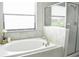 Bathroom featuring a soaking tub with tile surround and a separate glass-enclosed shower area next to a window at 13520 White Sapphire Rd, Riverview, FL 33579