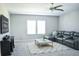 Cozy living room with a plush gray sectional, soft rug, and a modern ceiling fan at 13520 White Sapphire Rd, Riverview, FL 33579