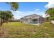 View of the backyard featuring an enclosed pool area, grassy lawn, and mature trees creating privacy at 13986 Bonnie Brae Dr, Largo, FL 33774