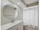 This bathroom features a single sink vanity, a circular mirror, and a shower-tub combo at 13986 Bonnie Brae Dr, Largo, FL 33774