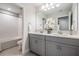 Bright bathroom featuring double vanity with gray cabinets, granite counters, and decorative floral arrangement at 14626 Horse Trot Rd, Lithia, FL 33547