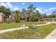 Charming two-story house with a lush green lawn, mature palms, black shingle roof, and two car garage at 15846 Glenarn Dr, Tampa, FL 33618
