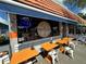 Outdoor seating at Tommy's Hideaway Wood Fired Pizza and Pub, with bright orange tables and a blue awning at 1801 52Nd S St, Gulfport, FL 33707