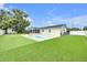 A view of the backyard showcasing green space, an inground pool and an enclosed patio at 2106 Sherbrook Dr, Valrico, FL 33594