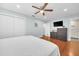 Bright bedroom featuring hardwood floors, a ceiling fan, a large closet, a TV, and an ensuite bathroom at 2106 Sherbrook Dr, Valrico, FL 33594