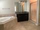 Bathroom showcasing a bathtub, shower with patterned glass, dark vanity, and tile floor at 2588 Bartolo Dr, Land O Lakes, FL 34639