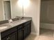Bathroom featuring a double vanity with granite countertops and dark cabinets at 2588 Bartolo Dr, Land O Lakes, FL 34639