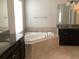 Bright bathroom featuring a soaking tub, dark vanity, and granite countertops at 2588 Bartolo Dr, Land O Lakes, FL 34639