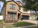 Charming two-story tan home with manicured front yard, a two-car garage, and stacked stone details at 2588 Bartolo Dr, Land O Lakes, FL 34639