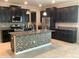 Stylish kitchen with dark cabinets, a granite island with mosaic accents, and stainless steel appliances at 2588 Bartolo Dr, Land O Lakes, FL 34639