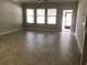 An empty living room with neutral paint, tile floors, three windows, and an exterior door at 2588 Bartolo Dr, Land O Lakes, FL 34639
