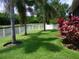 Spacious backyard with a white fence, mature palm trees, and well-maintained lawn at 27810 Sky Lake Cir, Wesley Chapel, FL 33544