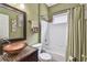 Bathroom with olive green walls, unique sink, and tiled shower and bathtub at 27810 Sky Lake Cir, Wesley Chapel, FL 33544