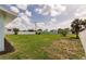A wide green backyard with an idyllic cloudscape above is surrounded by greenery and clean, white fences at 3316 Port Charlotte Blvd, Port Charlotte, FL 33952