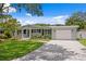 Charming single-story home featuring lush green lawn, beautiful landscaping, and a brick driveway at 5107 W Platt St, Tampa, FL 33609