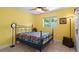 Cheerful bedroom with yellow walls, light-colored floors, a window view, and a comfortable bed with decorative metal frame at 5501 Highland S St, St Petersburg, FL 33705