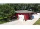 Red garage with white doors, decorative sconces, and a driveway under the shade of a tree at 5501 Highland S St, St Petersburg, FL 33705