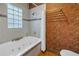 Bathroom showcasing a jetted tub, shower head, glass block window, and orange floral wallpaper at 635 Bay Ne St, St Petersburg, FL 33701