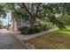 Wide shot of a charming yellow two-story home with a large tree in front and brick-paved pathway at 635 Bay Ne St, St Petersburg, FL 33701